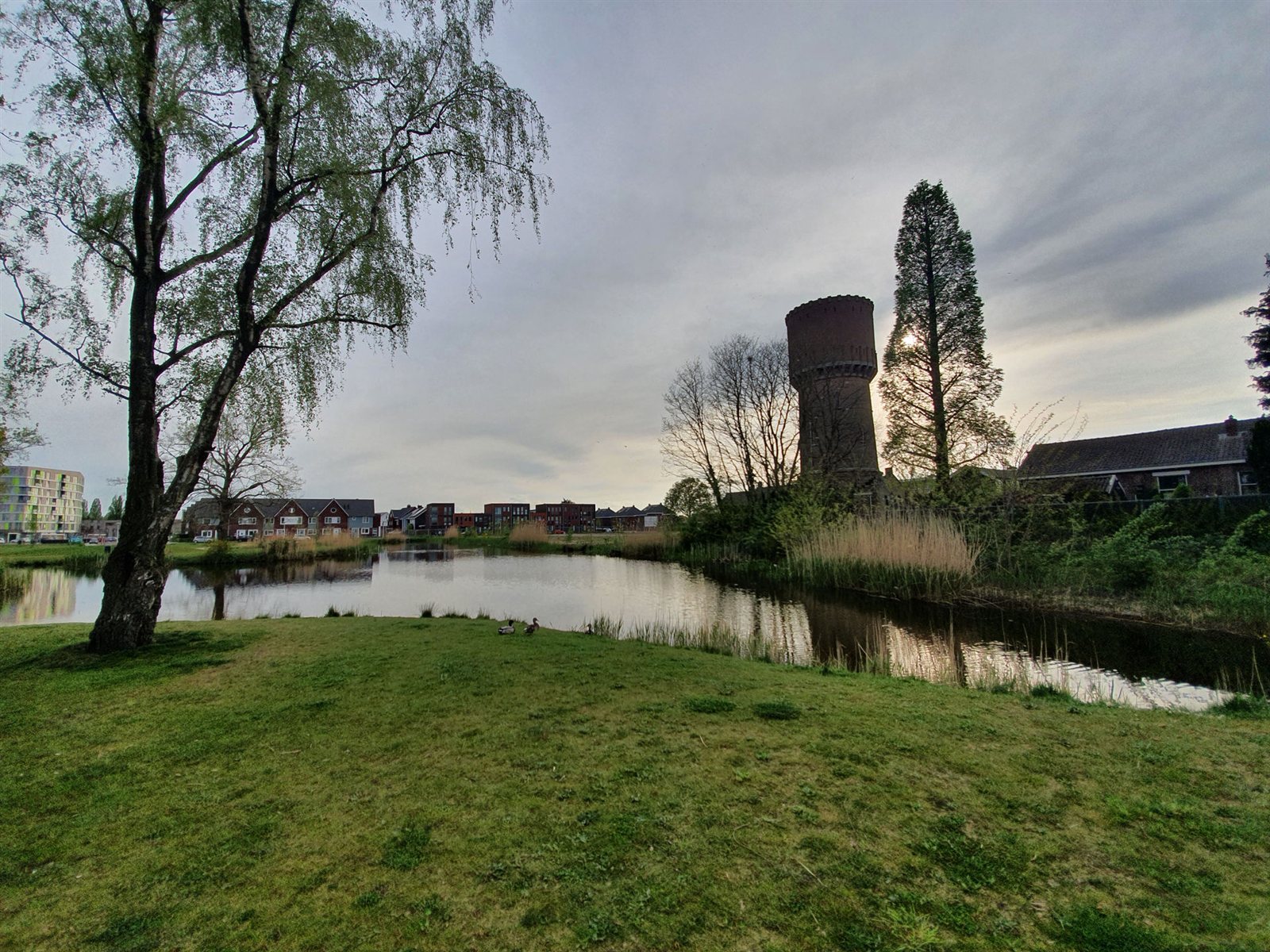 De historische bakstenen watertoren aan de vijver, omringd door bomen